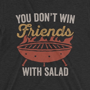 May include: A dark grey t-shirt with a vintage-style graphic of a grill and the text "You don't win friends with salad."