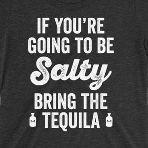 May include: A dark gray women's t-shirt with the text "If you're going to be Salty bring the Tequila" in white. The text is in a distressed font and there are two small images of tequila bottles on either side of the text.