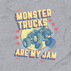 May include: A gray youth t-shirt with a vintage-style graphic of a monster truck. The graphic features the text "Monster Trucks Are My Jam" in a yellow, red, and blue color scheme.