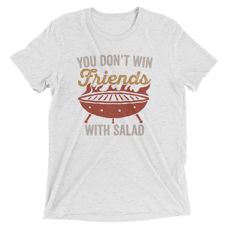 May include: White t-shirt with a distressed graphic of a grill with flames and the text "You don't win friends with salad."