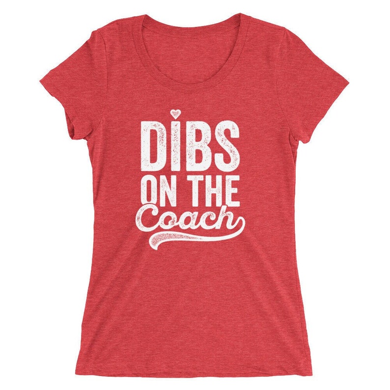 Puede incluir: Camiseta roja con el texto blanco "DIBS ON THE COACH", con un peque&ntilde;o coraz&oacute;n encima de la "i" de "DIBS". El texto tiene un aspecto envejecido. La camiseta tiene mangas cortas y cuello redondo.