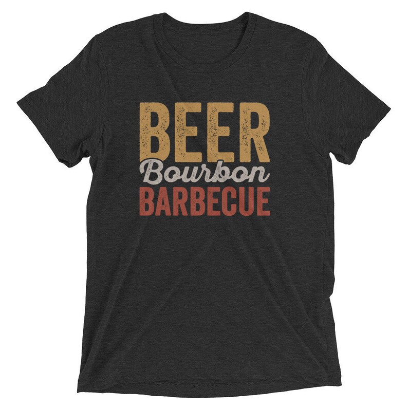 May include: A black t-shirt with the text "BEER Bourbon BARBECUE" in a vintage style font. The text is in shades of brown and red.