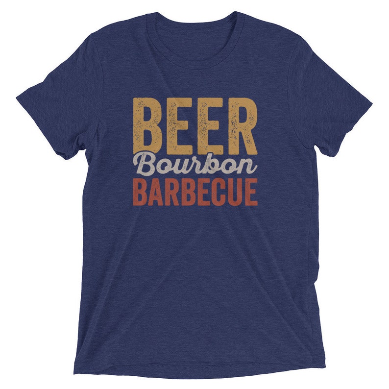 May include: A navy blue t-shirt with the text "BEER Bourbon BARBECUE" in a vintage style font. The text is in shades of yellow, orange, and red.