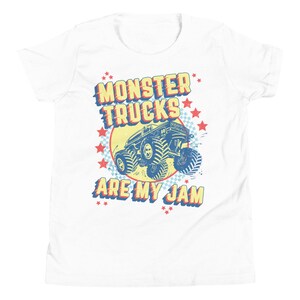 May include: White t-shirt with a retro-style graphic of a monster truck. The graphic features the text "Monster Trucks Are My Jam" in red, yellow, and blue lettering with stars around the truck.