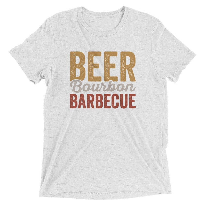 May include: White t-shirt with the text "BEER BOURBON BARBECUE" in a vintage style font. The text is in brown and red.