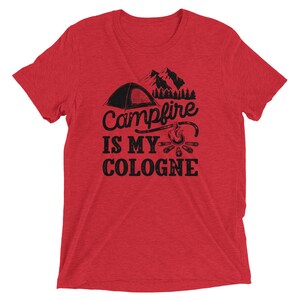 May include: Red short-sleeved t-shirt with a black graphic of a tent, mountains, and a campfire. The text reads "Campfire is my cologne".