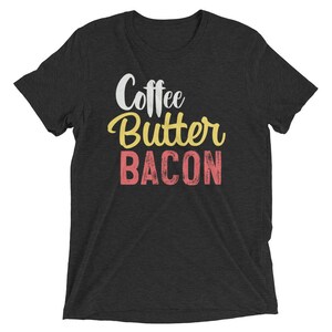 May include: A dark gray t-shirt with the text "Coffee Butter Bacon" in white, yellow, and pink lettering.