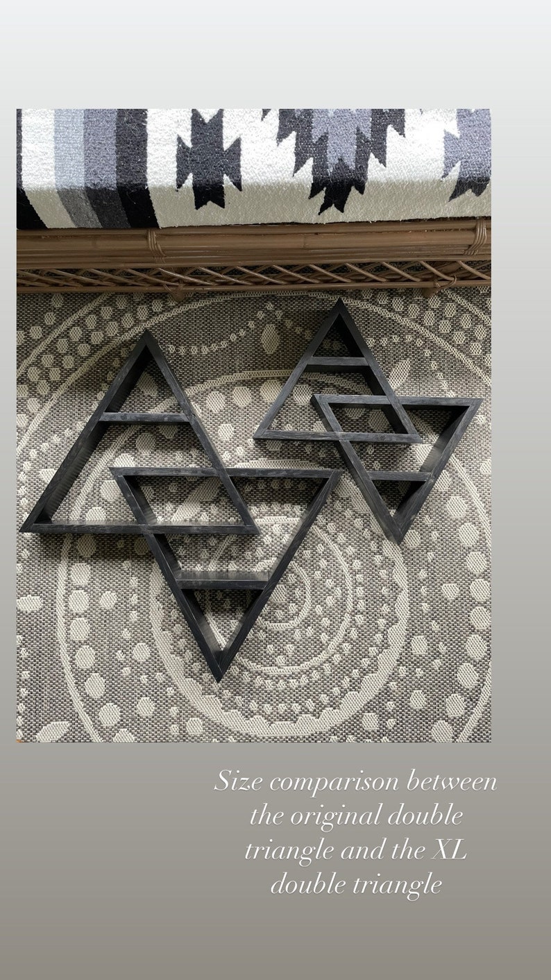 May include: Size comparison between the original double triangle and the XL double triangle. Two black wooden geometric triangle shelves are mounted on a wall. The larger shelf is twice the size of the smaller shelf.
