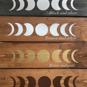 May include: Six wooden boards with different colored backgrounds, each featuring a moon phase design in a contrasting color. The colors are black and gold, black and silver, brown and white, brown and gold, brown and brown, and natural wood and white.