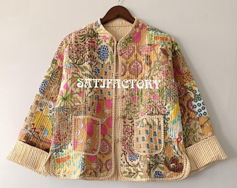 Peut inclure: Veste matelassée avec un motif patchwork de motifs floraux et botaniques dans les tons de rose, bleu, jaune et vert. La veste a un col mandarin, deux poches avant et une bordure rayée. Le mot "SATISFACTORY" est imprimé sur le devant.