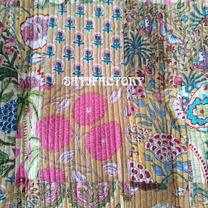 K&ouml;nnte beinhalten: Ein Patchwork-Textil mit verschiedenen floralen und botanischen Mustern in Rosa, Gr&uuml;n, Blau und Beige. Das Wort "SATISFACTORY" ist mittig aufgedruckt. Das Textil ist mit vertikalen N&auml;hten gesteppt.