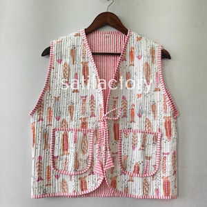 May include: A sleeveless, quilted vest with a white background and a repeating pattern of orange, pink, and black fish. The vest has two front pockets and a pink striped trim. A pink tie closure is at the front.