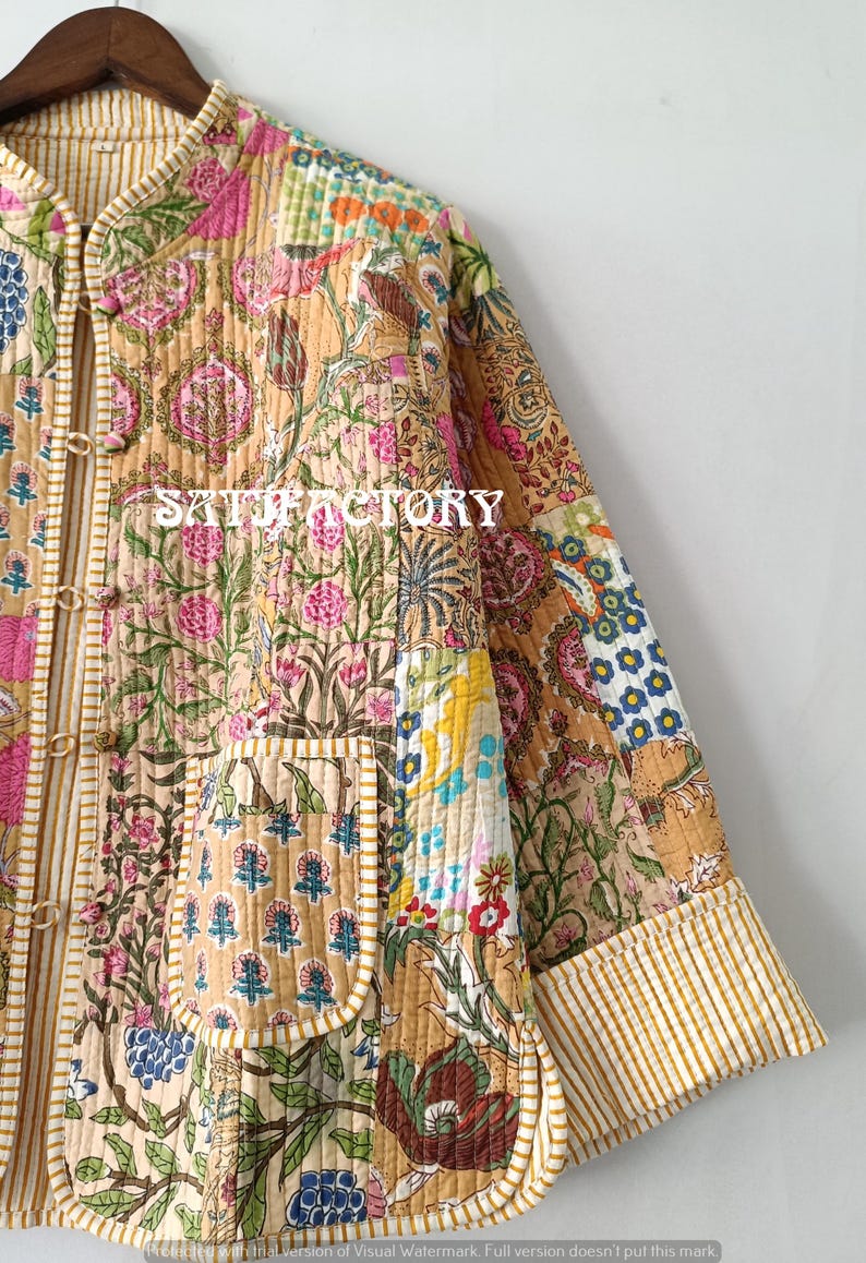 K&ouml;nnte beinhalten: Gesteppte Jacke mit Patchwork-Design. Sie hat verschiedene Blumen- und geometrische Muster in Beige, Rosa, Blau und Gr&uuml;n. Mit Stehkragen, zwei Taschen und Knopfleiste. Der Text "SATISFACTORY" ist sichtbar.