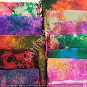 Puede incluir: Una colección de coloridas bufandas de tela teñidas con tinte anudado. Las bufandas muestran una variedad de colores, incluyendo rosa, verde, morado y naranja. La tela está doblada y apilada, mostrando los vibrantes patrones y texturas. La imagen es un primer plano de las bufandas.