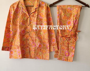 Puede incluir: Conjunto de pijama con estampado floral naranja y rosa, que incluye una camisa con botones y pantalones. La camisa tiene un ribete blanco y un bolsillo en el pecho. Los pantalones tienen cintura con cordón. El texto "SATISFACTORY" es visible.