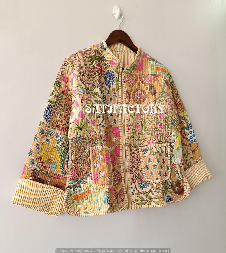 K&ouml;nnte beinhalten: Patchwork-Jacke mit floralem Muster in Rosa, Blau und Gelb. Die Jacke hat einen Stehkragen, zwei Taschen und gestreifte Manschetten. Der Text "SATISFACTORY" ist auf der Vorderseite aufgedruckt.