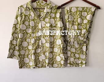 May include: Green and white floral print pajama set, including a button-down shirt and matching pants. The pajamas are displayed on wooden hangers against a neutral background. The word "SATISFACTORY" is printed on the shirt.