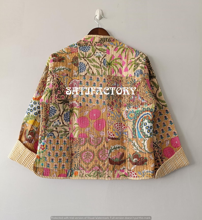 K&ouml;nnte beinhalten: Patchwork-Jacke mit verschiedenen Blumen- und Paisley-Mustern in Beige-, Rosa-, Blau- und Gr&uuml;nt&ouml;nen. Die Jacke hat einen Kragen und lange &Auml;rmel mit gestreiften Manschetten. Das Wort "SATIFACTORY" ist auf die Jacke gedruckt.
