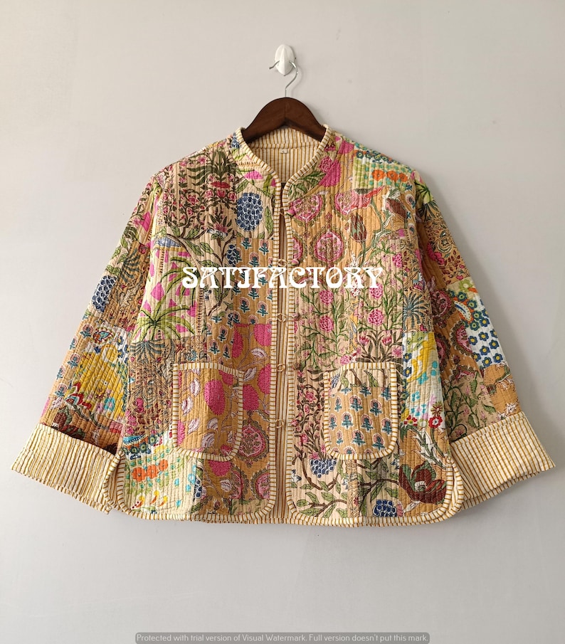 K&ouml;nnte beinhalten: Gesteppte Jacke mit Patchwork-Design mit Blumen- und Paisley-Mustern in Rosa, Gr&uuml;n und Gold. Die Jacke hat einen Stehkragen, zwei Vordertaschen und den Aufdruck "SATISFACTORY" auf der Vorderseite.