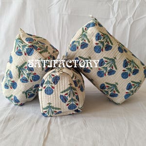 Puede incluir: Un conjunto de tres bolsas de tela color crema con un estampado floral azul y hojas verdes. Las bolsas son de diferentes tamaños y formas, con la palabra "SATISFACTORY" impresa en ellas.