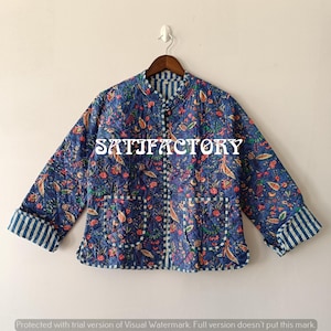 May include: A quilted blue jacket with a floral pattern, featuring a mandarin collar, two pockets, and striped cuffs. The jacket has the text "SATIFACTORY" across the front.