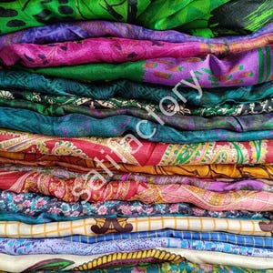 Peut inclure: Un empilement de tissus colorés et à motifs. Les textiles présentent une variété de couleurs, notamment du vert, du violet, du rose, du rouge et du bleu. Les tissus ont des motifs et des textures complexes, suggérant qu'ils sont en soie ou en matière similaire.