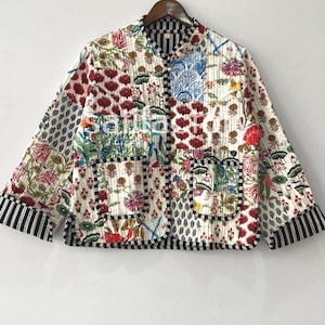 K&ouml;nnte beinhalten: Gesteppte Jacke mit Patchwork-Design. Sie zeigt Blumen- und geometrische Muster in Rot, Blau, Gr&uuml;n und Wei&szlig;. Die Jacke hat einen Stehkragen, zwei Taschen und schwarz-wei&szlig; gestreifte Manschetten und Bes&auml;tze.