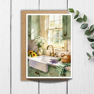 May include: A watercolor greeting card featuring a kitchen scene with a white farmhouse sink, a brass faucet, and green cabinets. A pitcher of white daisies, two sunflowers, a basket of bread, and a sprig of lavender sit on the counter.