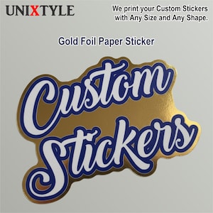 May include: Gold foil sticker with the words "Custom Stickers" in a white script font with a blue outline. The sticker has a gold background and is die-cut. The text "We print your Custom Stickers with Any Size and Any Shape" is also visible.