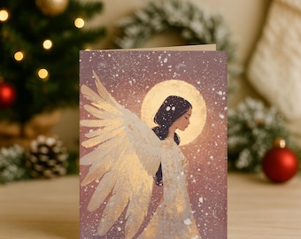 May include: A greeting card featuring an illustration of an angel with large, detailed wings. The angel is depicted in a flowing white gown, with a golden halo and wings. The background is a soft, snowy scene with a warm, golden glow.