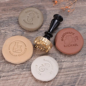 May include: Four clay circles with different designs and text, including "Handmade by Amanda", "Handmade by Michael", "Harlan Ceramics", and a floral design. A brass stamp with a floral design is also included.