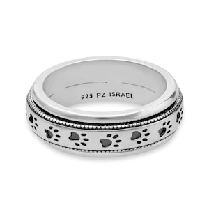 May include: A silver ring featuring a paw print design around the outer band. The ring has a rotating section with a series of paw prints. The text "925 PZ ISRAEL" is engraved on the inside of the ring.