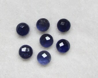 May include: Seven round, faceted, dark blue gemstones.