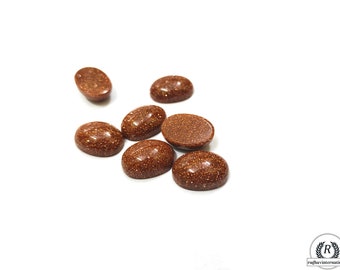 May include: A group of eight oval-shaped, brown, gemstone cabochons. The cabochons are smooth and have a speckled texture.
