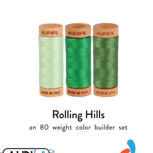 May include: Three spools of Aurifil thread in shades of green, labeled "Rolling Hills" and "an 80 weight color builder set". The Aurifil logo is also visible.