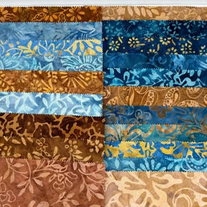 May include: A collection of fabric strips featuring batik patterns in various shades of blue, brown, tan, and gold. The strips are arranged in a grid, each displaying distinct floral, leaf, and abstract motifs with a textured, dyed appearance.