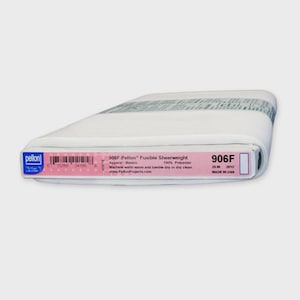 May include: A folded bolt of white Pellon 906F Fusible Sheerweight interfacing. The product label specifies 100% polyester material, 20 inch width, and machine wash instructions. The packaging includes a barcode and the Pellon brand logo.