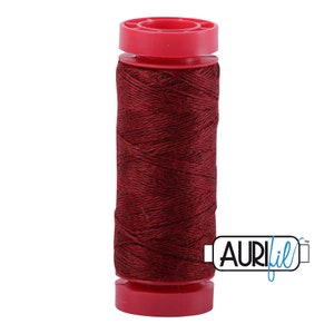 May include: A spool of dark red thread with a red plastic bobbin and the text "AURIfil" in blue.