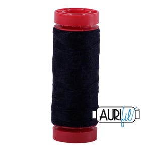 May include: A spool of dark navy blue sewing thread wound around a cylindrical core with bright red plastic caps at the top and bottom. The brand name AURIfil is printed in black and blue text on a white rectangular label at the bottom right.