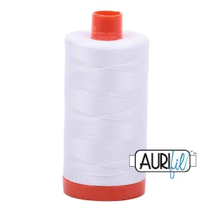 May include: A spool of white sewing thread wound around a cylindrical core with bright orange plastic caps at the top and bottom. The brand name AuriFil is printed in black and blue text on a white rectangular label attached to the spool.