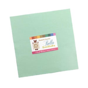 May include: A square, light green fabric piece with a label that reads "Elizabeth's Favorites Bella Solids" in white script. The label has a colorful border and a bear graphic. The fabric is a solid color, suitable for quilting and crafting.