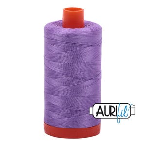 May include: A spool of vibrant purple sewing thread featuring a bright orange plastic top and base. The spool is wrapped in smooth, tightly wound thread and includes a white rectangular logo with the black and blue text AURIfil.