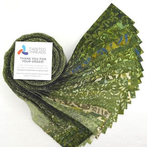 May include: A jelly roll of fabric strips in various shades of green, featuring batik-style patterns with floral and geometric motifs. A square white card is attached to the roll, displaying the Twisted Threads logo and contact information.