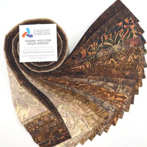 May include: A jelly roll of fabric strips featuring various brown, tan, and orange batik patterns with pinked edges. A white square card is attached to the top, displaying the Twisted Threads logo and text: THANK YOU FOR YOUR ORDER!