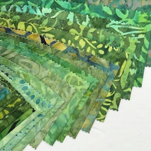May include: A collection of green fabric swatches in various shades, arranged in a fan shape. The fabrics feature leaf and abstract patterns in shades of green, teal, and yellow. The edges of the fabric are scalloped.
