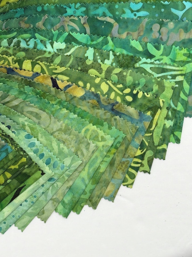 May include: A collection of green fabric swatches in various shades, arranged in a fan shape. The fabrics feature leaf and abstract patterns in shades of green, teal, and yellow. The edges of the fabric are scalloped.