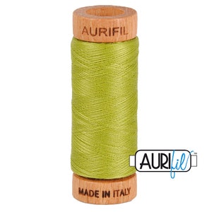 May include: A spool of Aurifil thread in a bright green color. The spool is made of wood and has the Aurifil logo printed on it. The text "Made in Italy" is printed on the bottom of the spool.