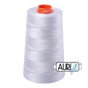 May include: A large spool of light gray sewing thread with a conical shape. The top features a bright orange plastic cap with the brand name Aurifil printed in white. The brand logo Aurifil is also displayed in the bottom right corner.