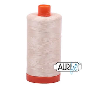 May include: A spool of light beige sewing thread with a bright orange plastic top and base. The spool features a cylindrical shape with tightly wound thread and the brand name Aurifil printed in black and blue text on the lower right side.