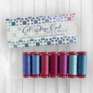 May include: A set of seven small spools of Aurifil 100% cotton thread in various shades of blue, pink, and purple. The spools are arranged below a card that reads "At Day's End" by Sarah Maxwell.